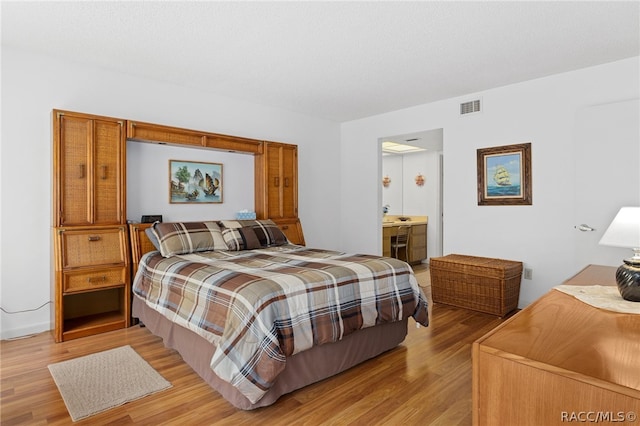 bedroom featuring ensuite bathroom and light hardwood / wood-style flooring