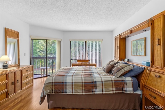 bedroom featuring access to exterior, a textured ceiling, and light wood-type flooring