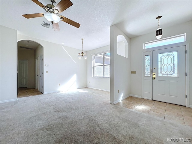 carpeted foyer entrance with baseboards, visible vents, arched walkways, tile patterned flooring, and a textured ceiling