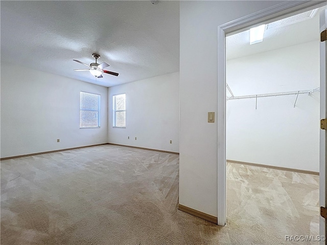 carpeted empty room with baseboards, a textured ceiling, and a ceiling fan