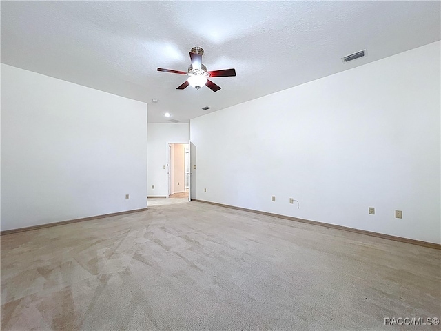 empty room with visible vents, light colored carpet, a textured ceiling, and baseboards