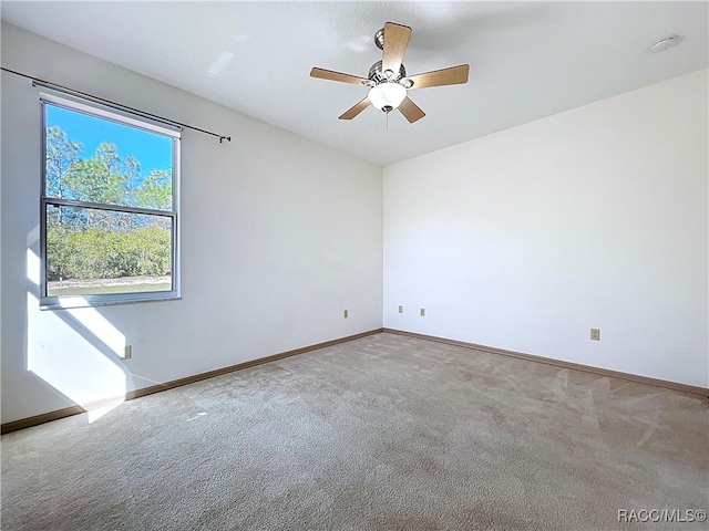 carpeted spare room featuring baseboards and ceiling fan