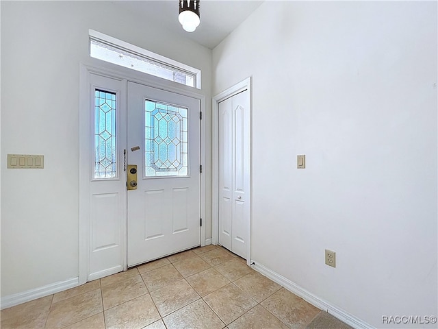 foyer entrance with light tile patterned floors and baseboards