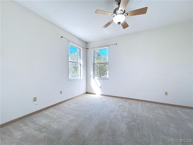 empty room with carpet flooring, a ceiling fan, baseboards, and a textured ceiling