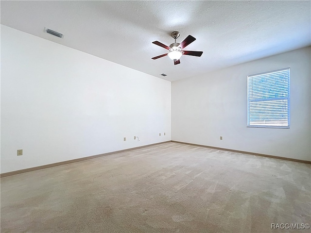 unfurnished room with baseboards, visible vents, ceiling fan, a textured ceiling, and light carpet