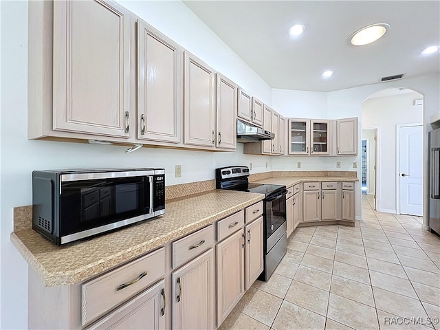 kitchen with under cabinet range hood, light countertops, appliances with stainless steel finishes, light tile patterned flooring, and arched walkways