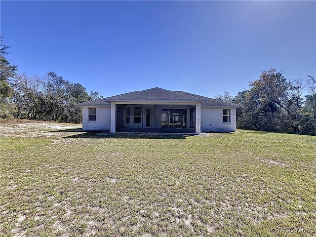 rear view of property featuring stucco siding, a lawn, and a sunroom