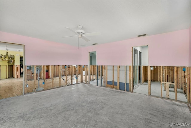 empty room with concrete floors, visible vents, and ceiling fan with notable chandelier