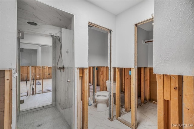 bathroom featuring marble finish floor, wooden walls, and toilet