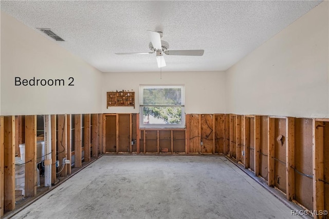 unfurnished room featuring a wainscoted wall, visible vents, ceiling fan, and a textured ceiling