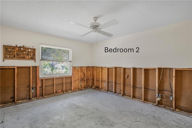 unfurnished room featuring a textured ceiling, a ceiling fan, and unfinished concrete floors