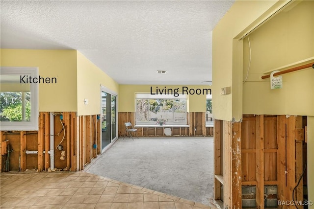 interior space featuring visible vents, wainscoting, light carpet, wooden walls, and a textured ceiling