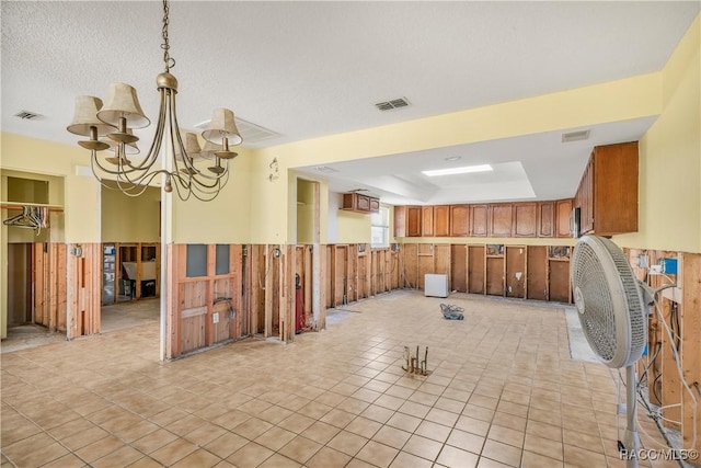 interior space with a wainscoted wall, wooden walls, visible vents, and an inviting chandelier