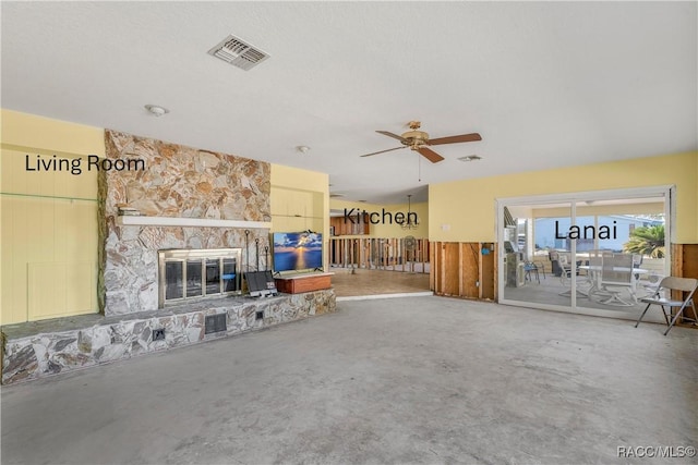 living room featuring a ceiling fan, visible vents, a stone fireplace, and unfinished concrete floors