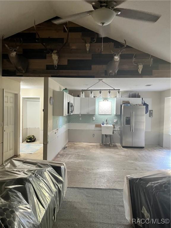 basement featuring stainless steel fridge, sink, and ceiling fan