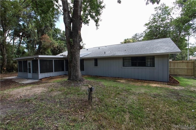 back of property with a sunroom and a yard