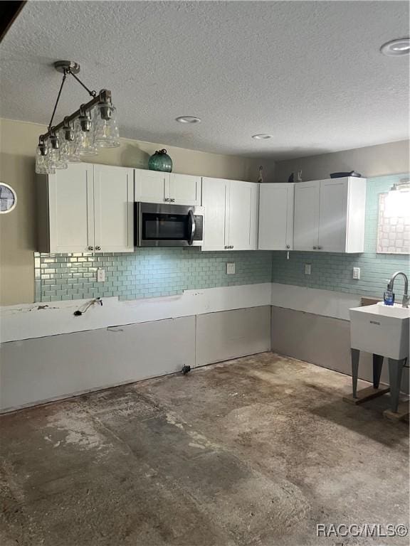 kitchen featuring white cabinetry, hanging light fixtures, concrete floors, and a textured ceiling