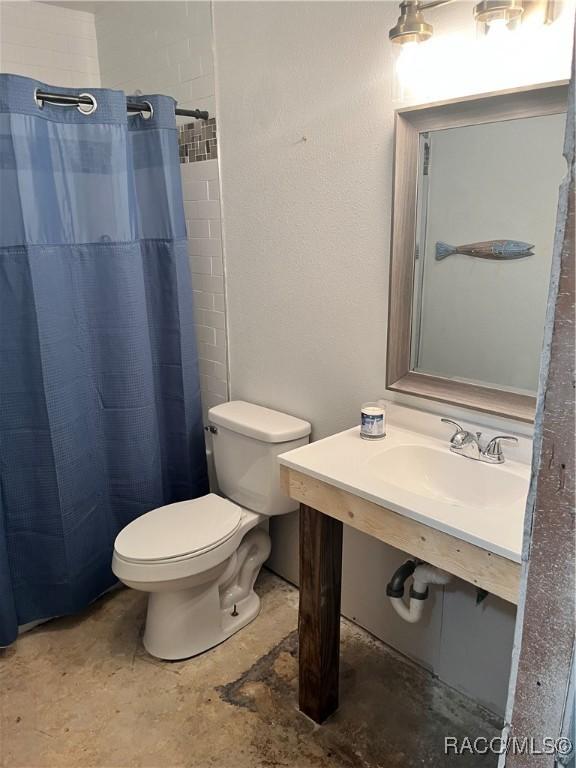 bathroom featuring a shower with shower curtain, toilet, and sink