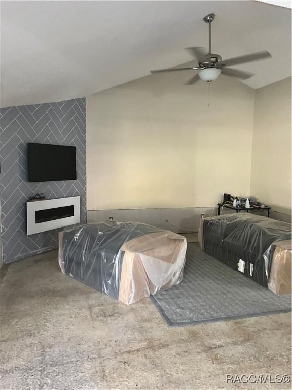 bedroom featuring a large fireplace, vaulted ceiling, and ceiling fan