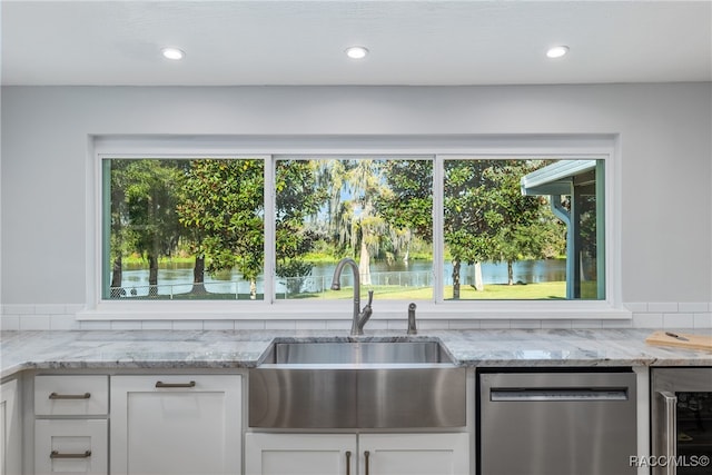 kitchen featuring light stone counters, stainless steel dishwasher, sink, white cabinetry, and wine cooler