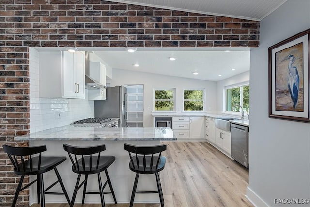 kitchen with lofted ceiling, sink, appliances with stainless steel finishes, tasteful backsplash, and kitchen peninsula