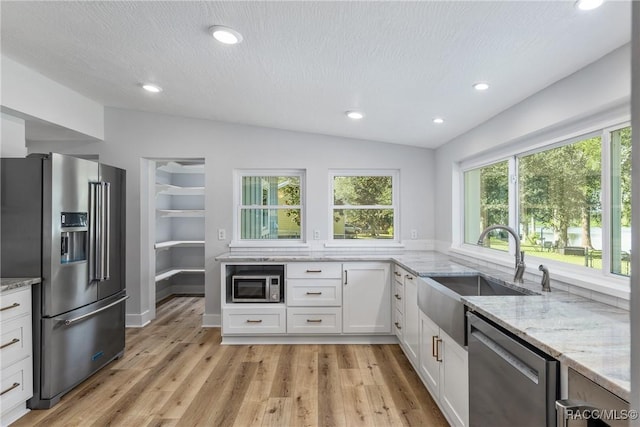 kitchen featuring sink, light stone counters, a textured ceiling, white cabinets, and appliances with stainless steel finishes