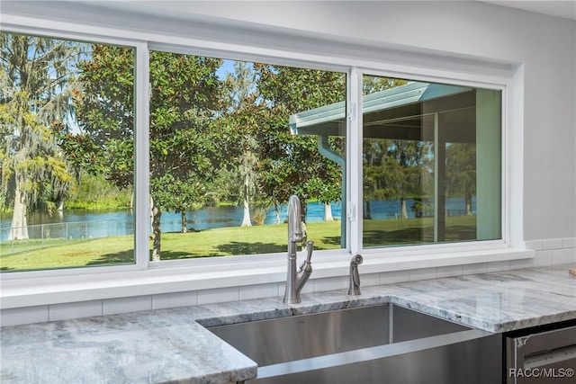 details featuring dishwasher, a water view, light stone countertops, and sink