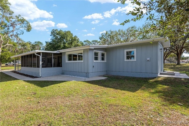 rear view of property with a lawn and a sunroom