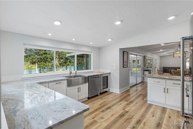 kitchen with light wood-type flooring, light stone counters, stainless steel dishwasher, white cabinets, and wine cooler