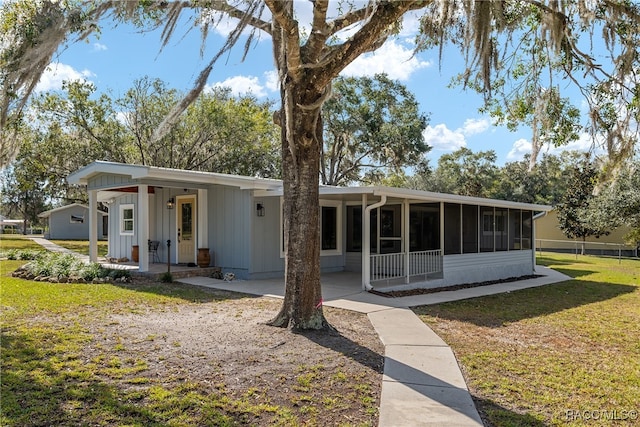 rear view of house featuring a yard and a sunroom