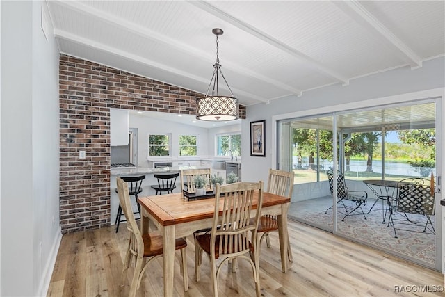 dining area with lofted ceiling with beams, brick wall, and light wood-type flooring