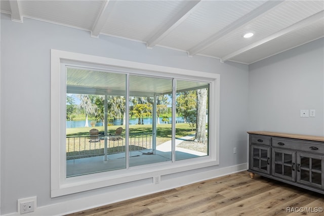 empty room featuring beamed ceiling, a water view, and wood-type flooring