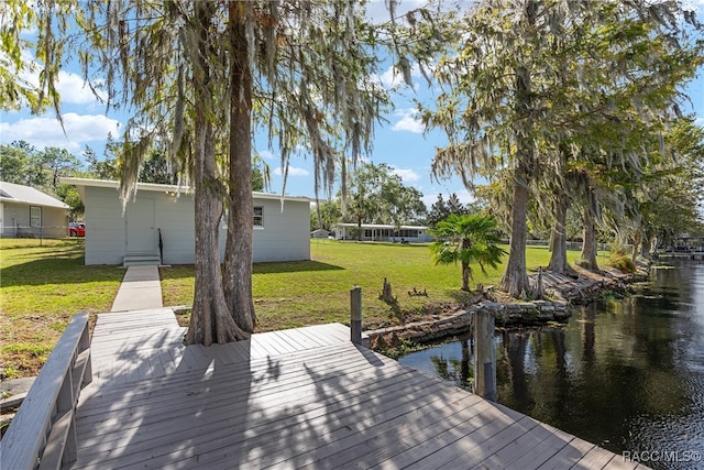 view of dock featuring a lawn and a water view