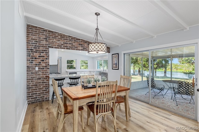 dining area with vaulted ceiling with beams, sink, brick wall, and light hardwood / wood-style flooring