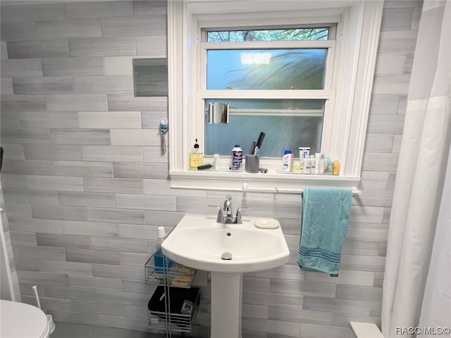 bathroom featuring toilet and tile walls