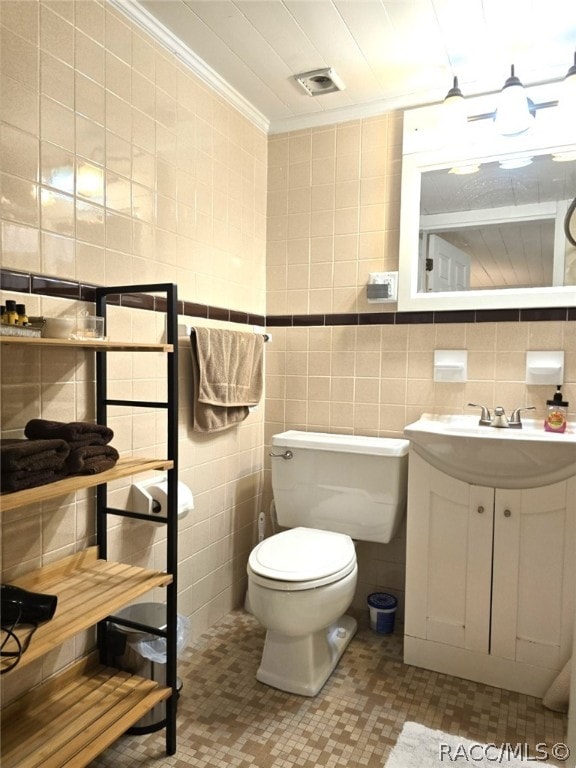 bathroom with vanity, toilet, ornamental molding, and tile walls