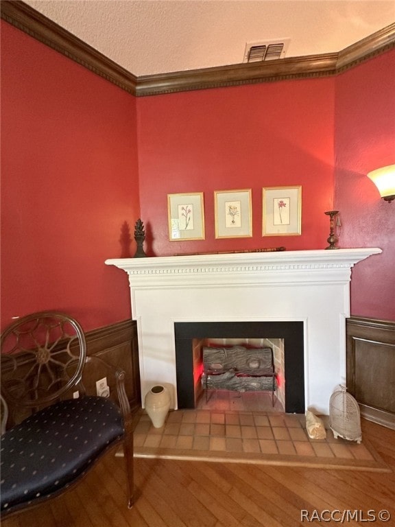 details with wood-type flooring, ornamental molding, and a tiled fireplace