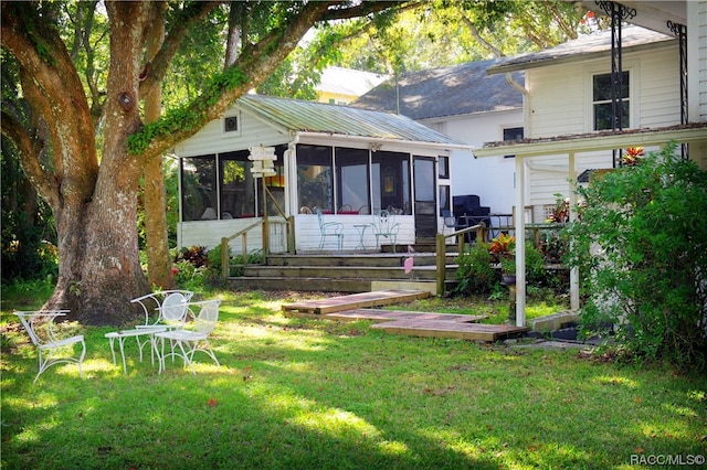 rear view of house featuring a sunroom and a lawn