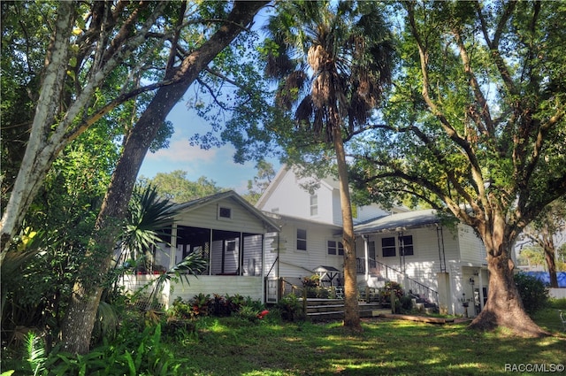 rear view of property featuring a sunroom and a yard