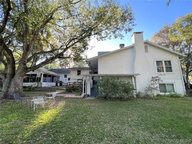 rear view of house with a sunroom and a lawn