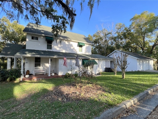 view of front of house featuring a front yard, a porch, and an outbuilding