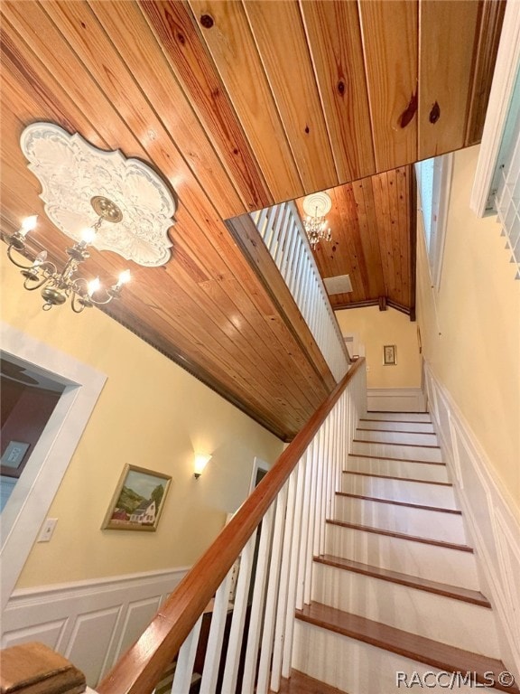 staircase featuring wood-type flooring, vaulted ceiling, a notable chandelier, and wood ceiling