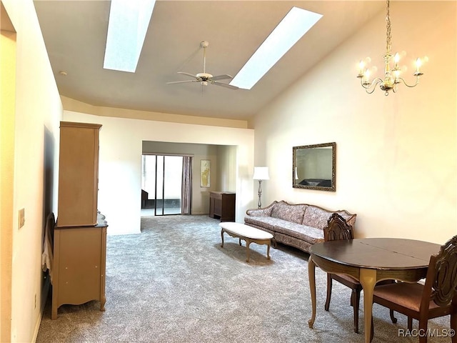 carpeted living room with ceiling fan with notable chandelier, high vaulted ceiling, and a skylight