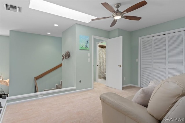 interior space featuring ceiling fan, light colored carpet, and a skylight