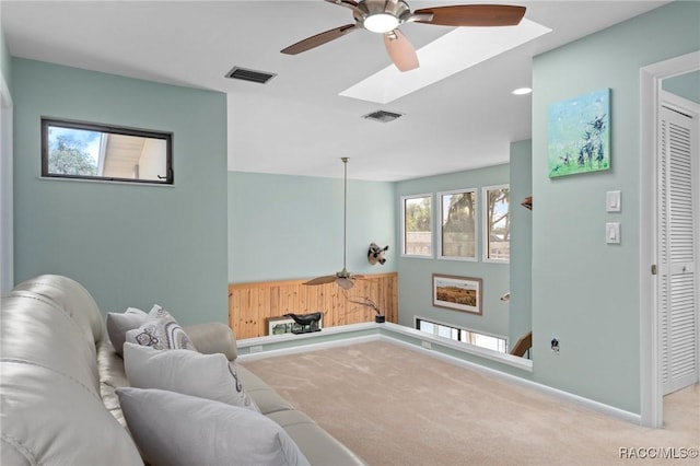 carpeted living room featuring ceiling fan and a skylight