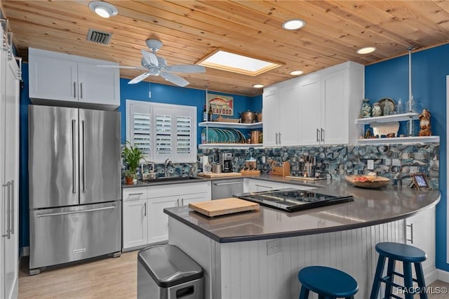 kitchen with wooden ceiling, white cabinets, a kitchen breakfast bar, sink, and stainless steel appliances