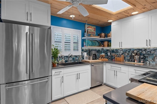 kitchen with white cabinets, sink, a skylight, wood ceiling, and stainless steel appliances