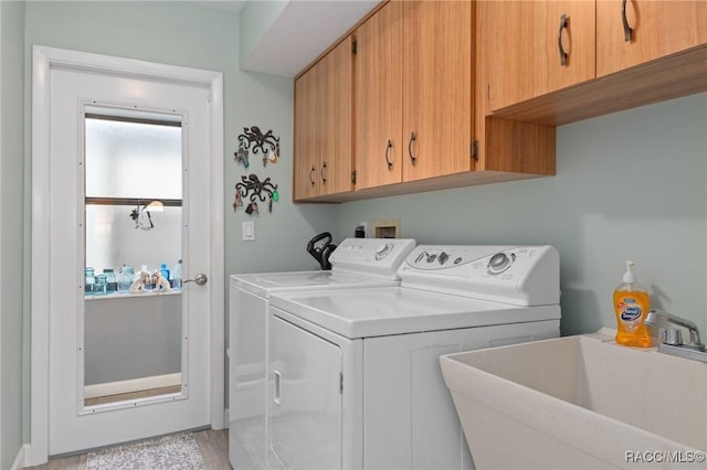 washroom featuring light hardwood / wood-style floors, cabinets, sink, and washing machine and dryer