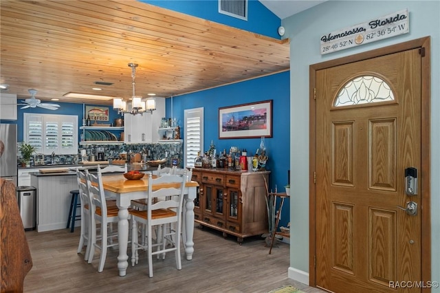 dining space featuring hardwood / wood-style floors, wood ceiling, and ceiling fan with notable chandelier