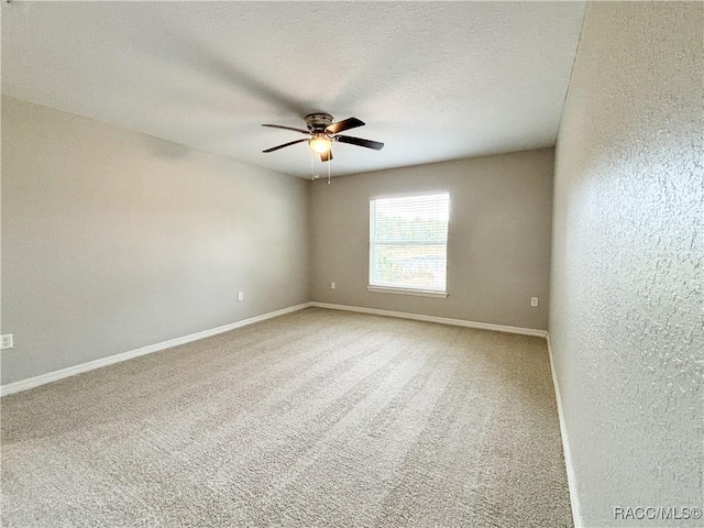 unfurnished room featuring carpet, ceiling fan, a textured ceiling, and baseboards